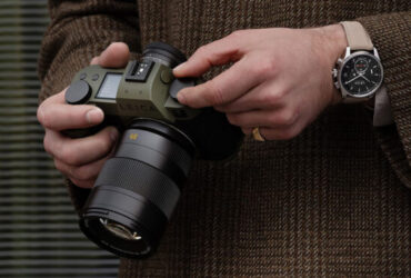 a person in a brown tweed coat holds a green leica camera 660x371 1